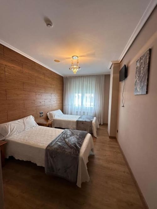Habitación doble en Hostal Asber de Zamora con camas gemelas, cabecero de madera y luz natural desde la ventana
