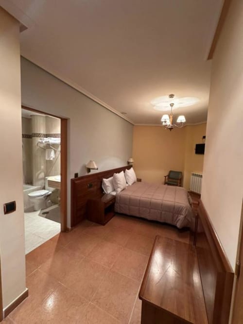 Habitación doble en Hostal Asber en Zamora con cama de madera, baño privado y suelo de barro cocido