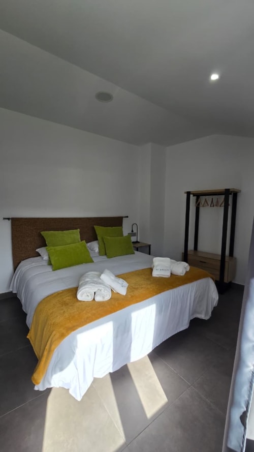 Habitación moderna del Hotel Spa El Batán con camas gemelas, almohadas verdes, plaid amarillo y techo oscuro en Castillo de Locubín