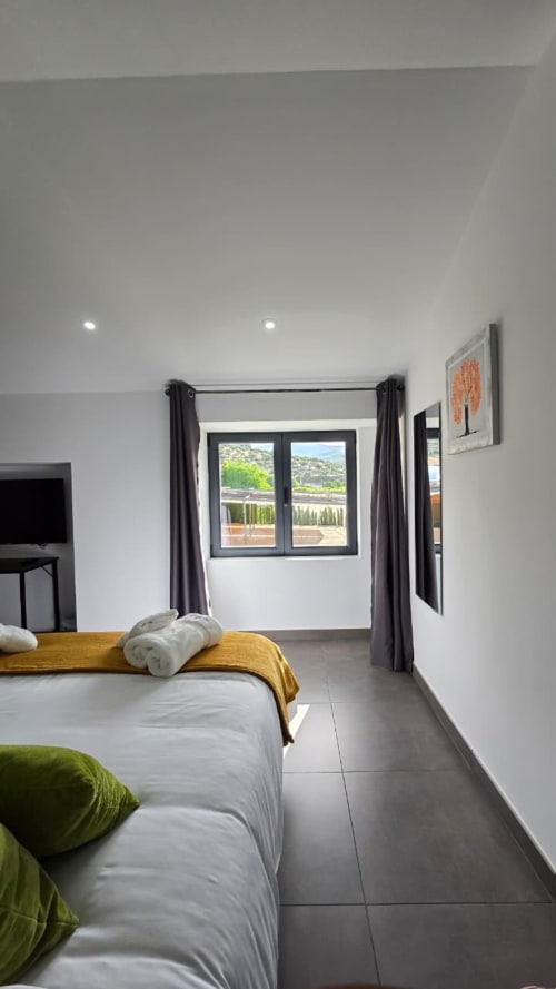 Habitación moderna en El Batán Hotel Spa con vistas a la montaña, cama doble con manta amarilla, cortinas oscuras y acceso a terraza