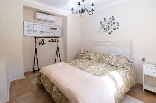 Dormitorio luminoso con ropa de cama floral en El Batán Hotel Spa de Castillo de Locubín, cama de metal blanco y decoración moderna