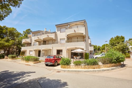 Experiencias Encant B&B en Calafat: edificio blanco moderno con terrazas, coche rojo y paisajismo mediterráneo
