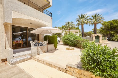 Terraza de Experiencias Encant BnB en Calafat con sombrillas blancas, asientos y vistas al jardín mediterráneo