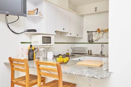 Cocina moderna en Experiencias Encant B&B en Calafat con muebles blancos, encimeras de granito y sillas de madera