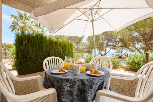 Patio frente al mar en Experiencias Encant con sombrillas, mesa de desayuno y vistas al Mediterráneo en Calafat
