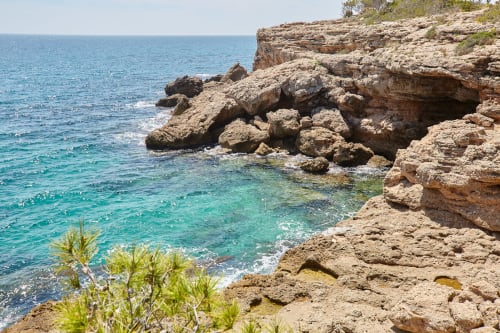 Aguas turquesas del Mediterráneo y acantilados rocosos de piedra caliza en Calafat, España, cerca del alojamiento Experiencias Encant.