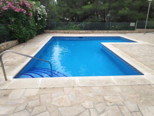 Piscina del alojamiento Experiencias Encant BnB en Calafat con agua azul, patio de piedra y jardines floridos
