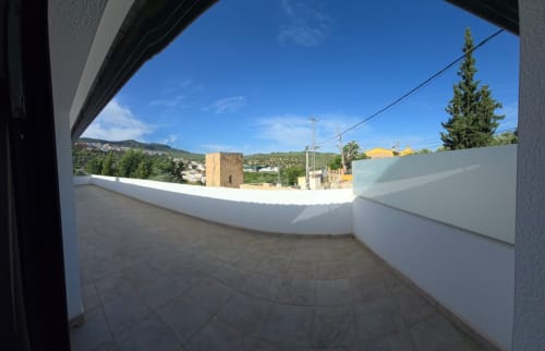 Amplia terraza con barandillas blancas con vistas al pueblo de Castillo de Locubín y montañas verdes en El Batán Hotel Spa