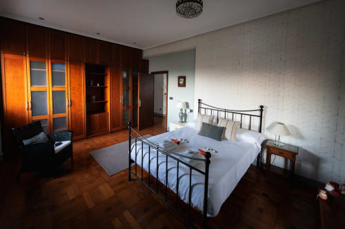 Spacious bedroom at Casa Señorial Sasueta in San Sebastián with wooden herringbone flooring, metal bed frame, and