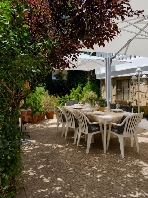 Zona de comedor al aire libre sombreada en Las Casitas de Noe, Layos con sombrillas blancas, plantas en macetas y elegante disposición de mesas