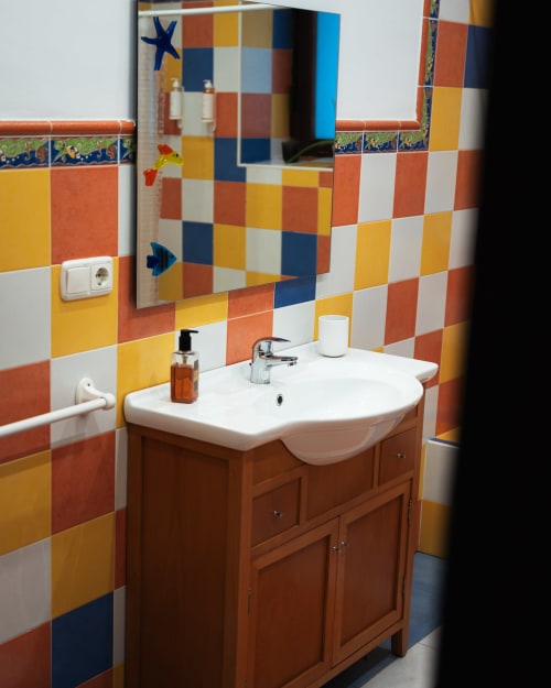 Colorful checkerboard bathroom at Casa Señorial Sasueta in San Sebastián with yellow, orange, white and navy tiles, wooden