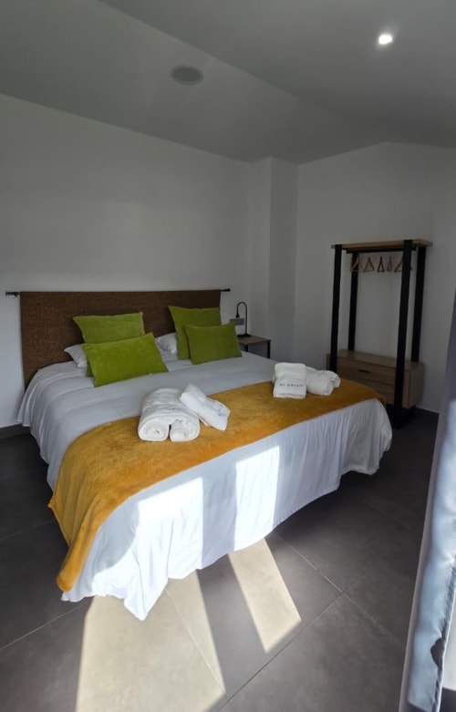 Habitación moderna del Hotel Spa El Batán con dos camas, almohadas verde lima y muebles de madera oscura en Castillo de