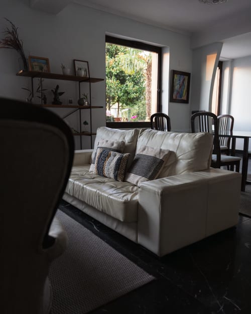 Bright living room at Casa Señorial Sasueta in San Sebastián with cream sofa, black chairs, shelving, and garden views