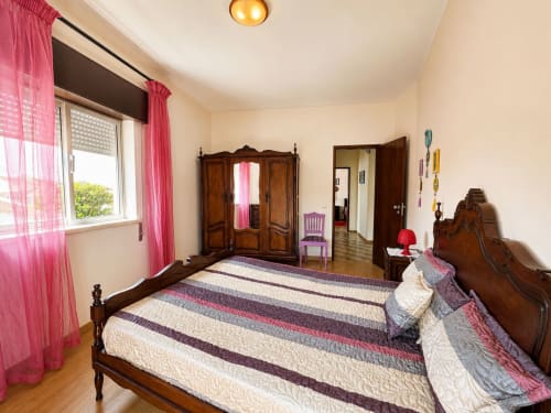 Quarto espaçoso no apartamento Casa Amarela em Zonas Mágicas, Lagos, com cama de madeira, cortinas rosa e vista para a cidade