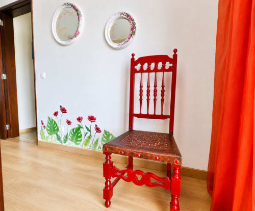 Cadeira vermelha decorativa no apartamento Casa Amarela em Zonas Mágicas, Lagos, com arte floral na parede e espelhos redondos