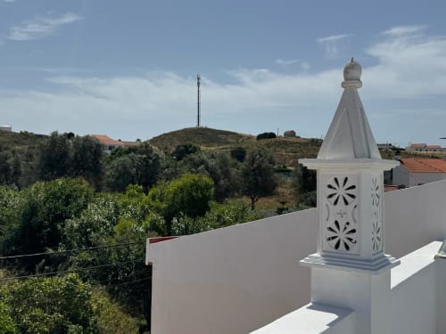 Chaminé branca decorativa na cobertura da Casa Amarela com vista para os olivais e colinas de Lagos, Portugal