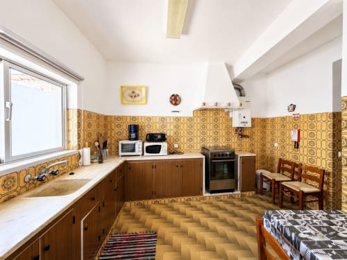 Cozinha retrô com azulejos amarelos no apartamento Casa Amarela, Lagos, com armários de madeira e eletrodomésticos vintage
