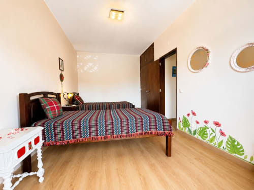 Quarto da Casa Amarela, Zonas Mágicas em Lagos com cama de madeira, roupa de cama listrada e decoração floral nas paredes