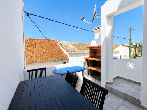 Terraço Casa Amarela em Lagos com mesa de jantar, cadeiras azuis e vista da cidade sob céu limpo