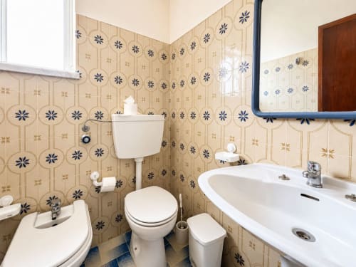 Banheiro compartilhado no apartamento Casa Amarela, Zonas Mágicas Lagos, com azulejos padronizados, vaso sanitário, pia e espelho