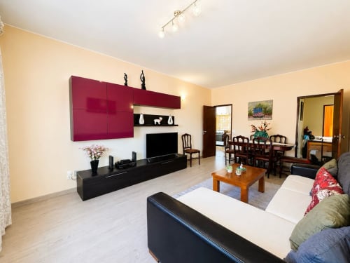 Ampla sala de estar da Casa Amarela em Lagos com mobiliário moderno, armários em tom bordô e vista para a cidade