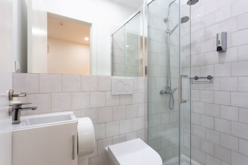 Modern bathroom in Lisbon Poets Inn Suite Casal with white tile walls, glass shower enclosure, sink and toilet