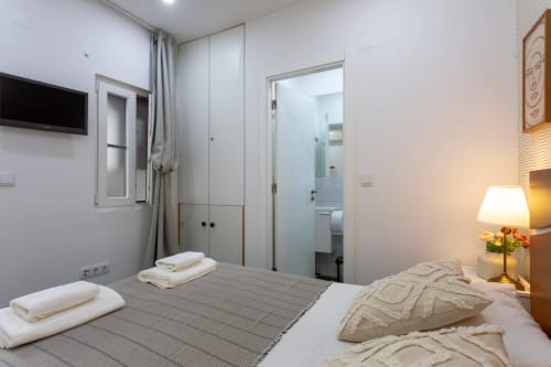 Modern double bedroom at Lisbon Poets Inn hostel with bed, en-suite bathroom, TV, and contemporary furnishings