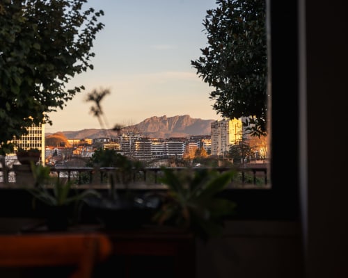 Vista de la hora dorada del paisaje urbano de San Sebastián y la montaña Urgull enmarcados por vegetación desde Casa Señorial Sasueta