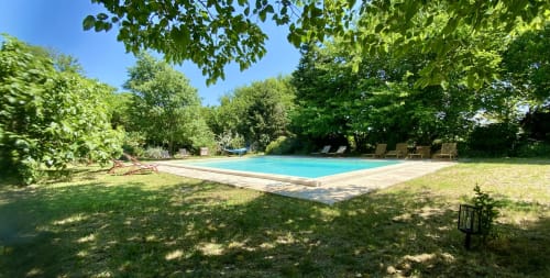 Piscine ensoleillée du Le Mas de la Soie B&B à Violes, entourée d'arbres verdoyants et de transats