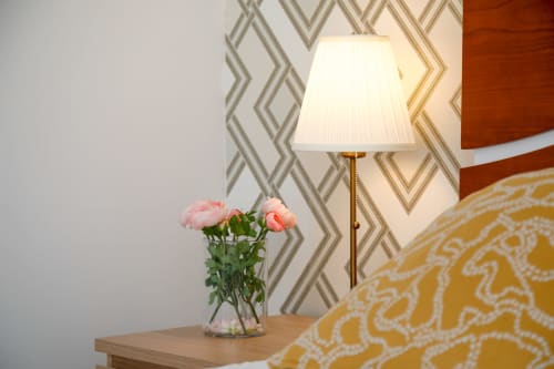 Bedside table with pink flowers and lamp in Lisbon Poets Inn double room, patterned wallpaper background