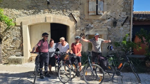 Cinq cyclistes posant avec leurs vélos devant la maison d'hôtes Le N°9 à Argeliers, façade en pierre de charme