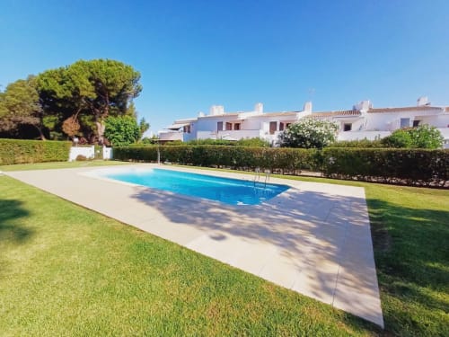 Apartamento de praia no Algarve com piscina, jardim bem cuidado, sebes, edifícios brancos e céu azul