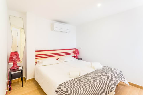 Quarto claro no apartamento da praia Barracuda em Algarve Beach Holidays com cabeceira vermelha, roupa de cama branca, ar condicionado e