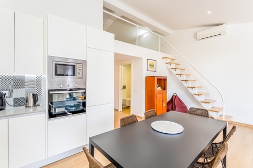 Cozinha e sala de jantar modernas no apartamento Barracuda na Praia do Algarve, com escadaria e armário laranja