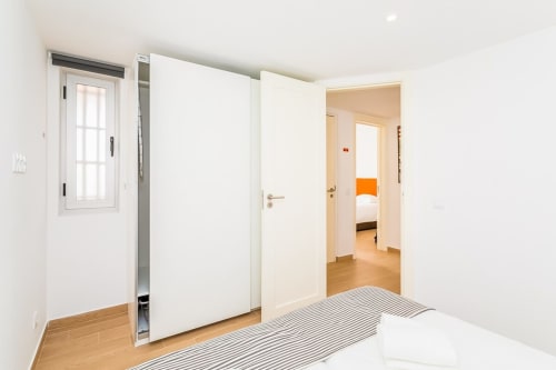 Quarto moderno e luminoso no apartamento Barracuda, Praia do Algarve, com assoalho em madeira, portas brancas e acesso direto à suite