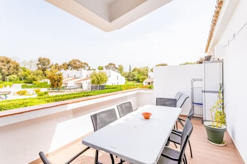 Terraço espaçoso do apartamento Barracuda na Praia do Algarve com mesa de refeições, vistas para o mar e jardins exuberantes