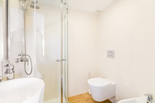 Banheiro moderno no apartamento Barracuda em Algarve Beach Holidays com chuveiro, sanitário e piso em madeira