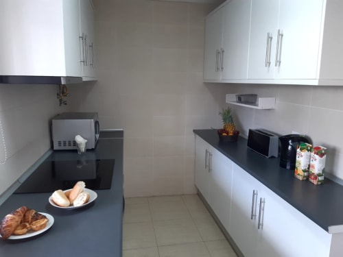 Cozinha moderna no apartamento MARSOL na Praia do Algarve com bancadas pretas, armários brancos e frutas frescas.