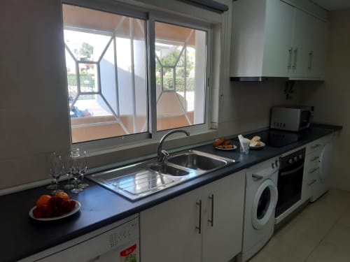 Cozinha moderna no apartamento de praia MARSOL no Algarve com pia, fogão, máquina de lavar e vista para o jardim