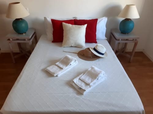 Apartamento Marsol na Praia do Algarve apresenta cama queen com almofadas vermelhas, abajures verde-azulado e acolhimento aconchegante
