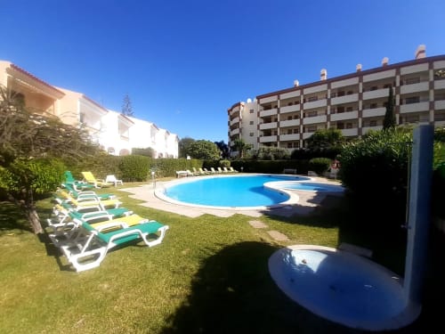 Férias na Praia do Algarve - Piscina do apartamento MARSOL com espreguiçadeiras, gramado e edifícios sob céu azul