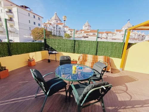 Terraço na cobertura do Algarve Beach Holidays com mesa de jantar, vistas da vila costeira e pérgola amarela