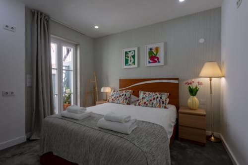 Lisbon Poets Inn double bedroom with wood headboard, colorful pillows, modern decor, and balcony access in Lisboa