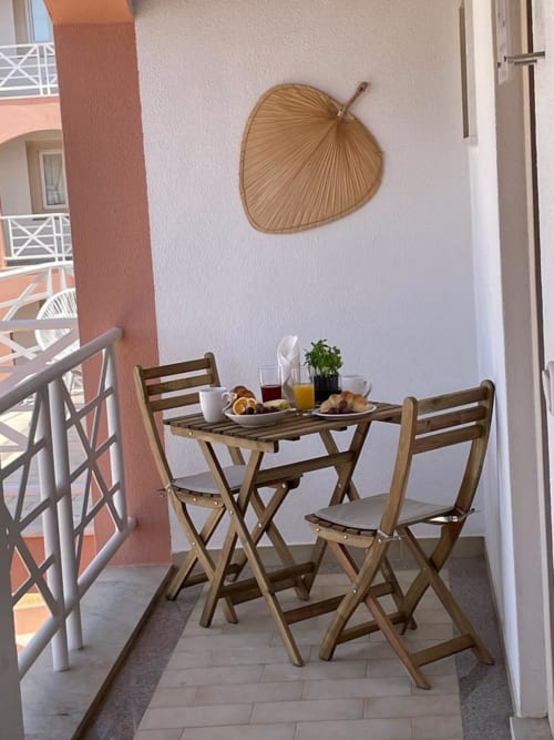 Aconchegante área de refeições na varanda do Algarve Beach Holidays com mesa de madeira, cadeiras, café da manhã e decoração em vime