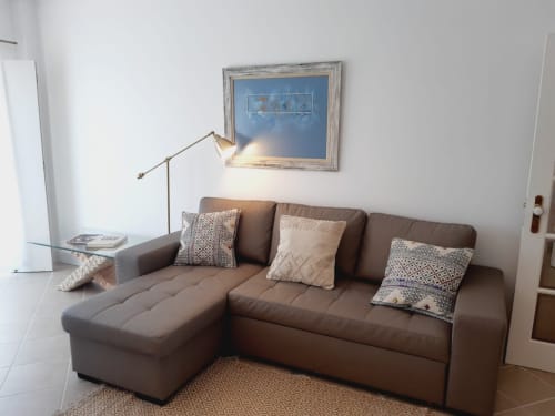 Sala aconchegante no apartamento Algarve Beach Holidays com sofá seccional bege, almofadas decorativas, luminária de piso e azul