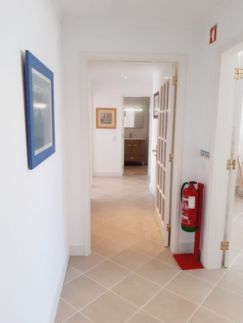 Corredor limpo do apartamento de praia VILLALUSA no Algarve com piso em azulejo, portas brancas e extintor