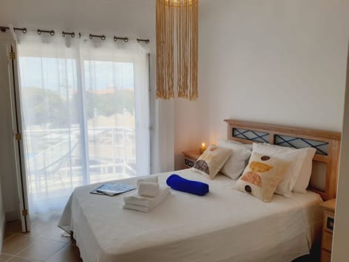 Quarto luminoso no apartamento VILLALUSA Beach no Algarve com varanda vista mar, cama de madeira e mobiliário moderno