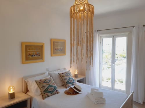 Quarto luminoso em apartamento de praia do Algarve com decoração em macramé, almofadas estampadas e portas de vidro com vista para a piscina