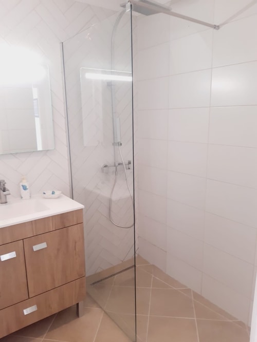 Casa de banho moderna com duche em vidro temperado, móvel de madeira e paredes de azulejo branco na villa Algarve Beach Holidays
