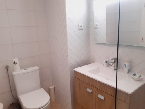 Banheiro moderno no apartamento VILLALUSA Beach em Algarve Beach Holidays com azulejos em espinha de peixe brancos, vaidade de madeira e